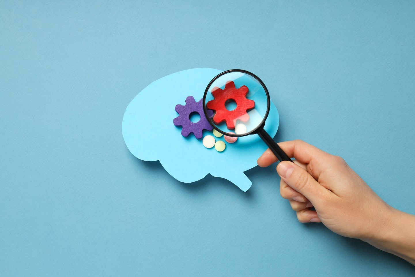 paper-brain-on-blue-background-and-hand-with-lens